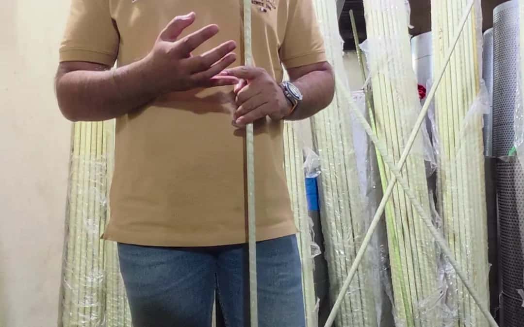 Holding a pale green FRP bar in front of stacked bars