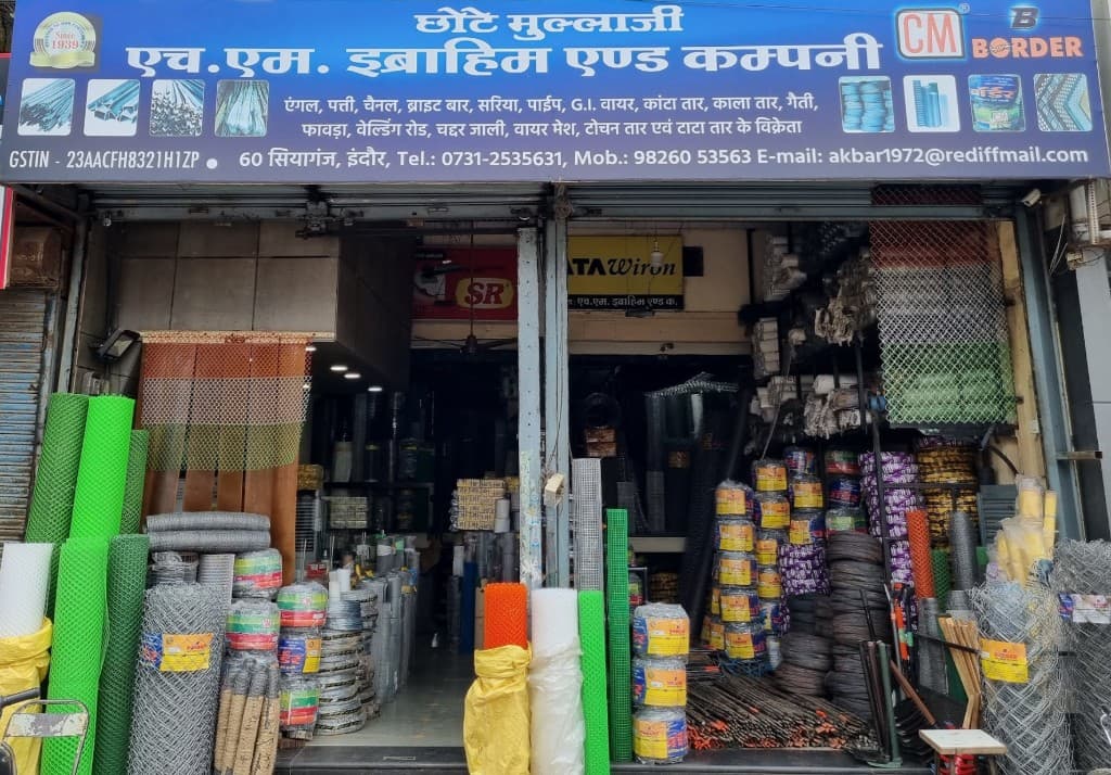 H.M. Ibrahim & Company storefront at 60 Siyaganj, Indore — angles, flats, channels, bright bars, rebar, pipes, wire mesh, and hardware on display.