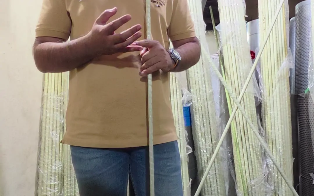 Holding a pale green FRP bar in front of stacked bars