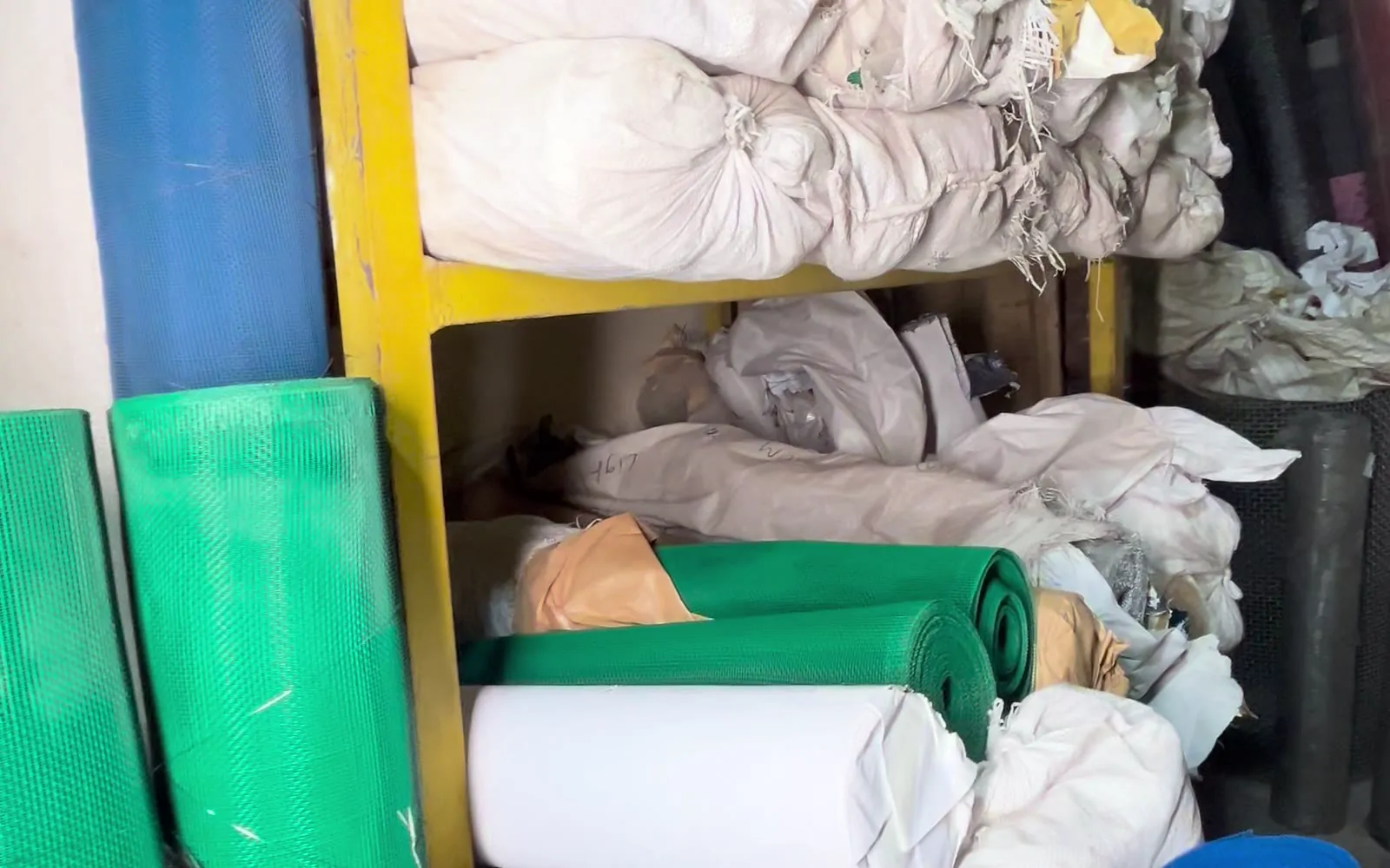 Green and blue mosquito net rolls on a shelf