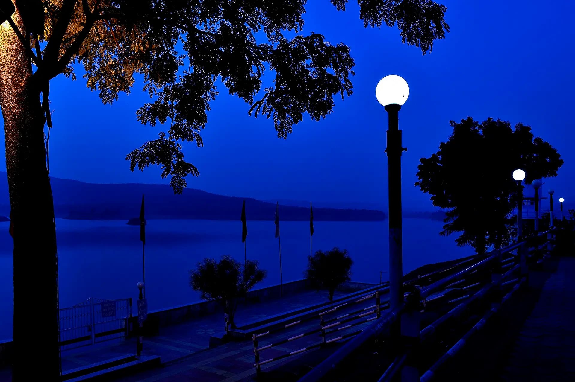 Choral dam near Mhow, Indore, at dusk, with lamp posts along the lakeside walk and hills across the water