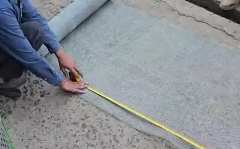 Measuring a mesh roll with a tape on the ground