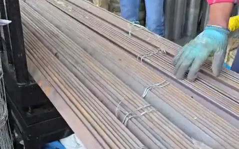 Gloved hand checking a bundle of steel bars