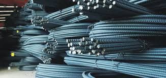 Bundles of ribbed TMT steel bars stacked in an industrial warehouse